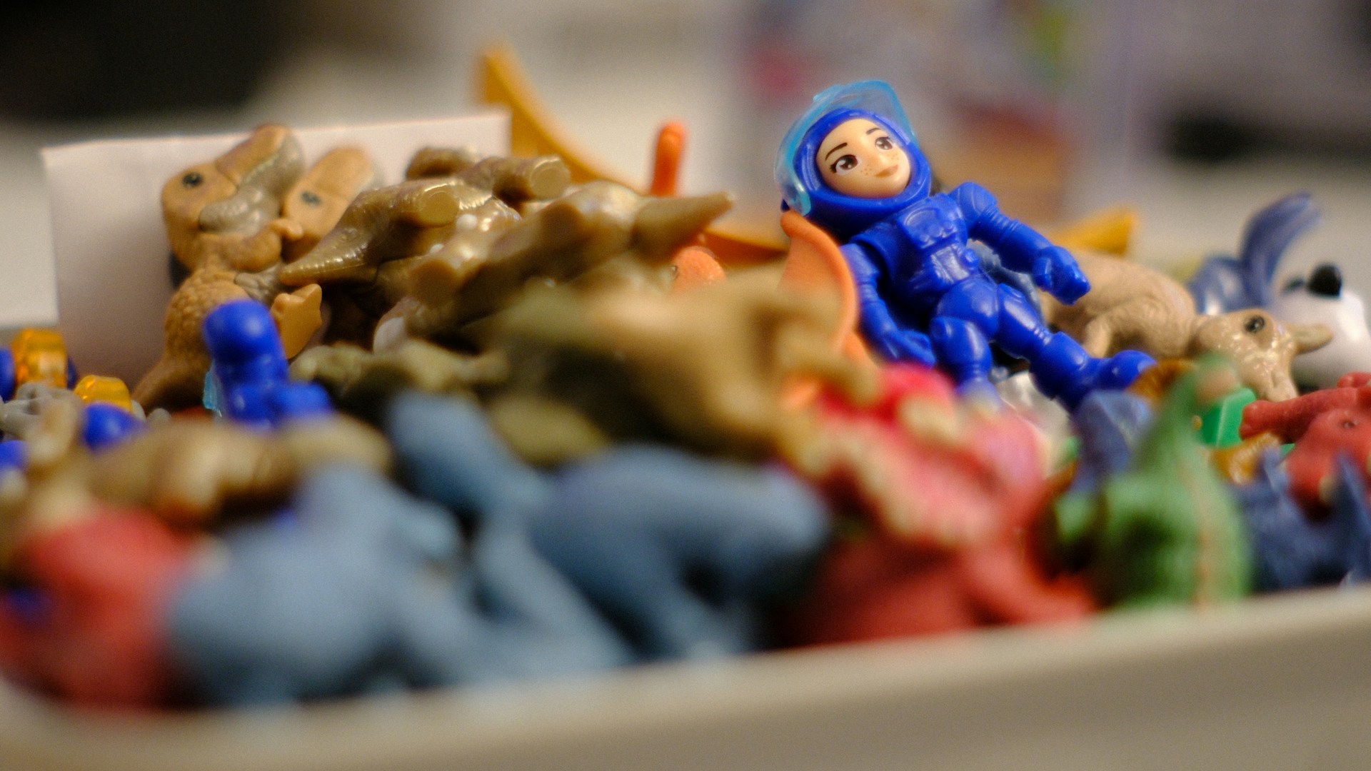 A blue astronaut toy among many colorful small toys.