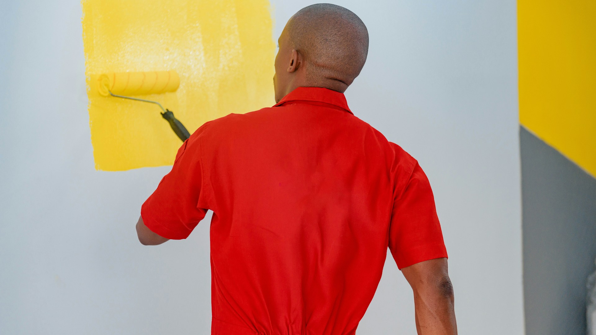 a man painting a wall with yellow paint